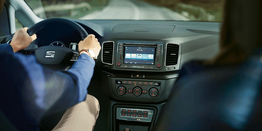 Hombre sentado en el interior de SEAT Alhambra conduce por carretera.