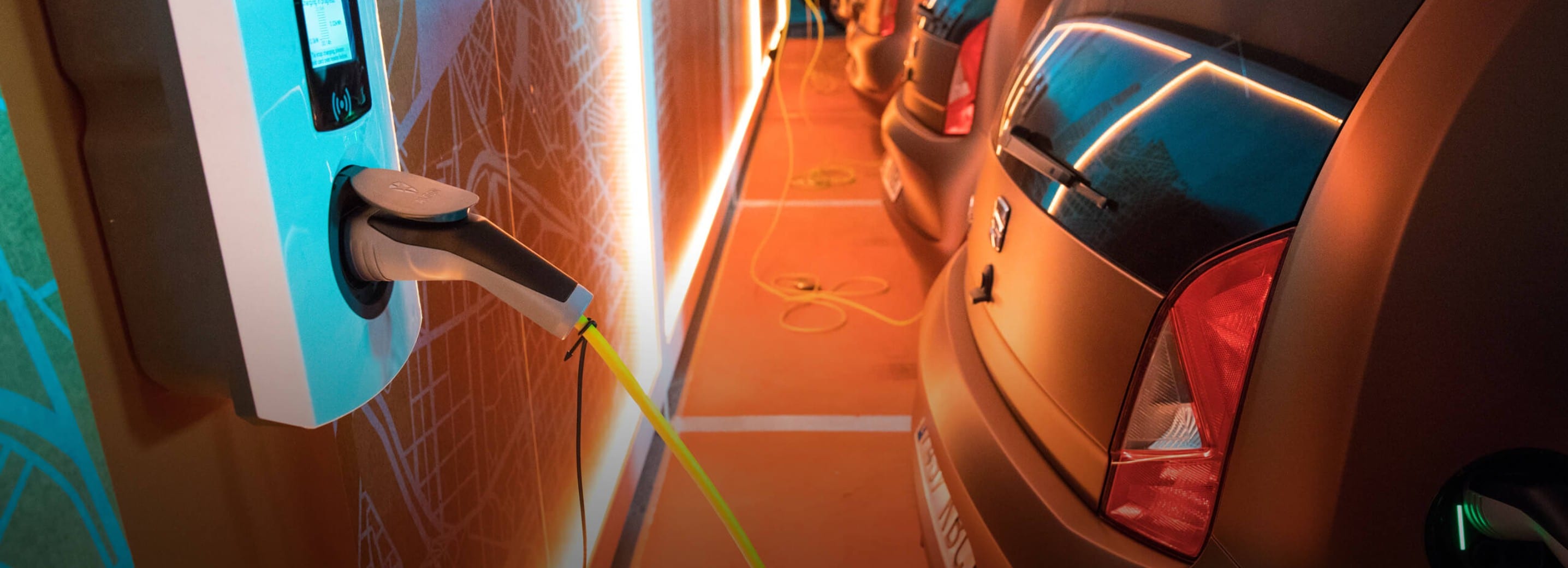 Flota de SEAT Mii aparcada en estacionamiento comercial mientras cargan sus baterías en un punto de carga público.