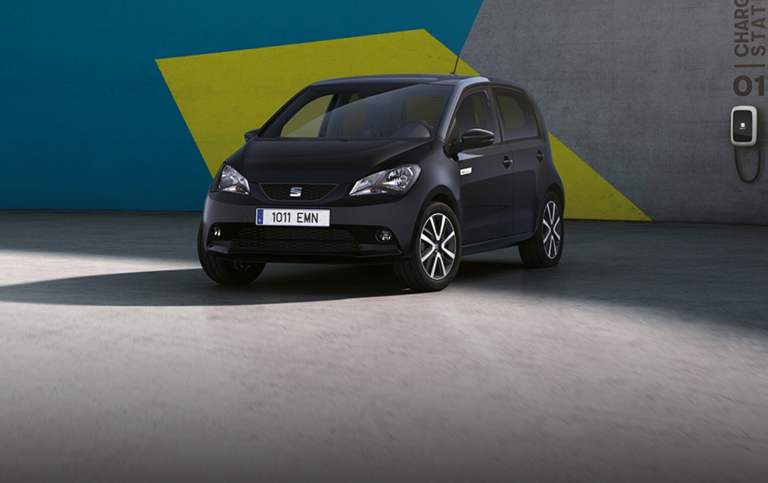 SEAT Mii electric 100% sostenible de color negro aparcado junto punto de carga de pared.