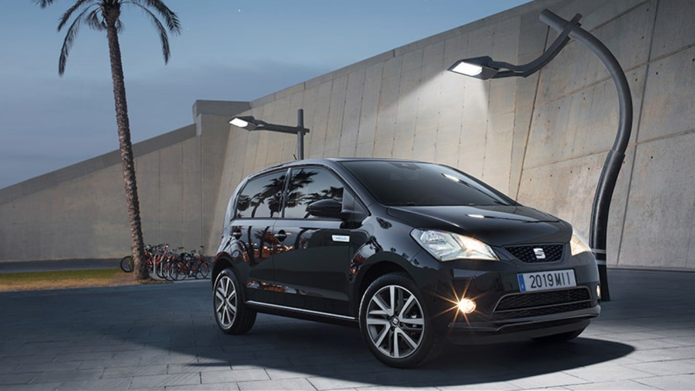 SEAT Mii Electric 100% eléctrico aparcado en un estacionamiento de playa bajo unas farolas de diseño.