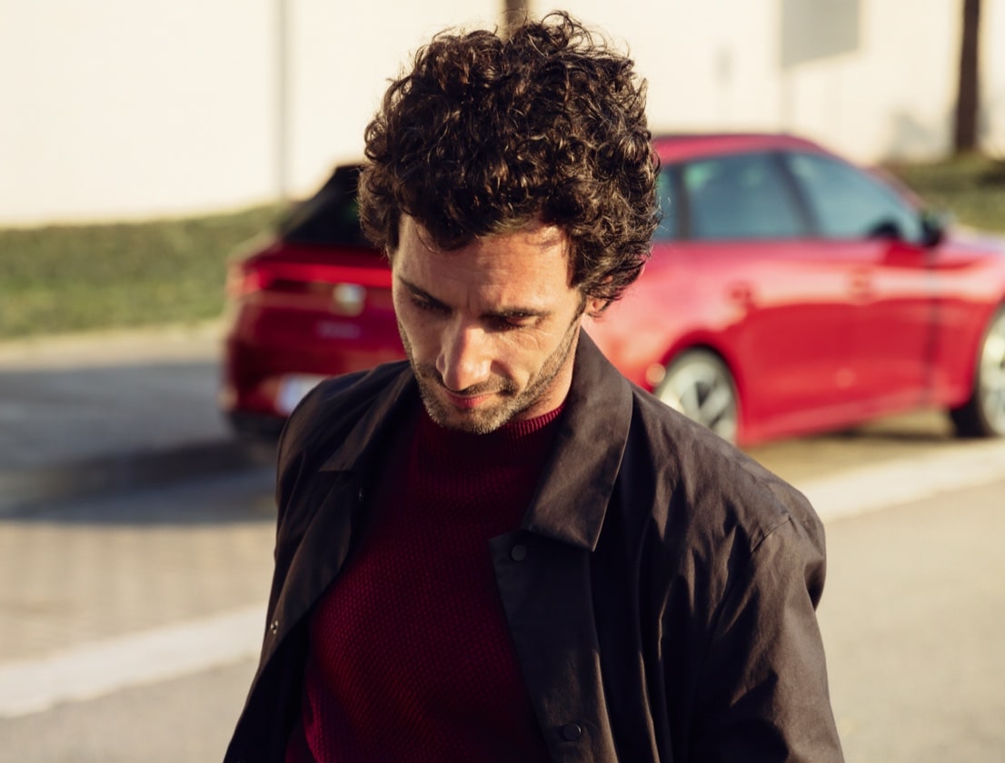 pareja hablando junto a un SEAT León color rojo Desire aparcado