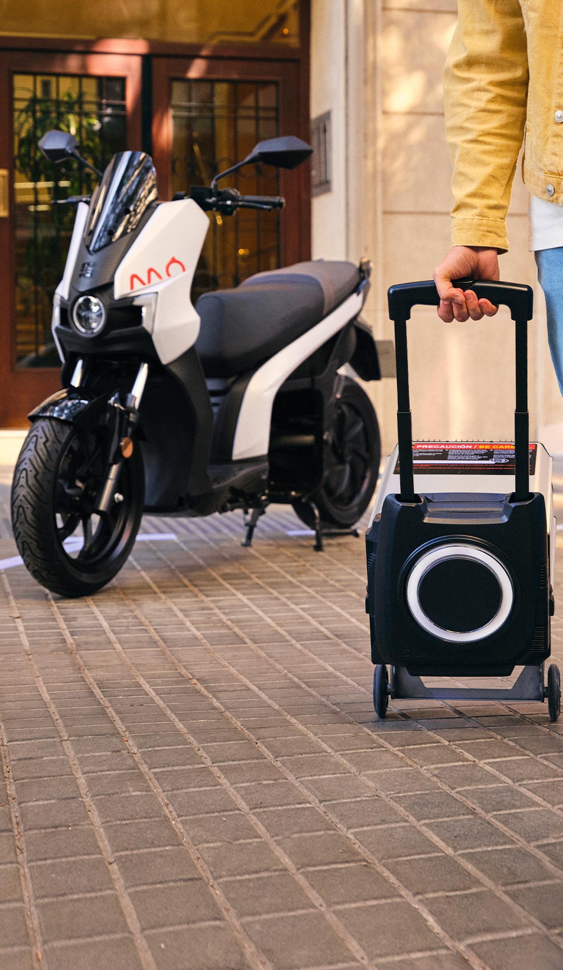 hombre sentado junto a su scooter SEAT MÓ 125 eléctrico con hasta 137 km de autonomía