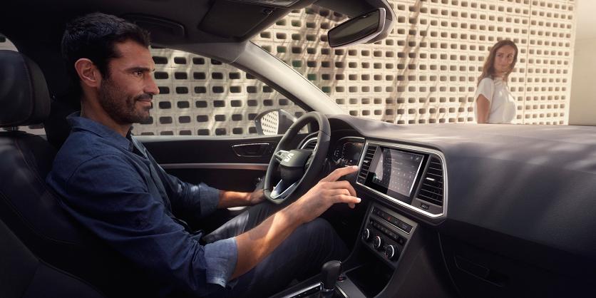 Hombre en interior de SEAT León configura los mapas en pantalla infoentretenimiento