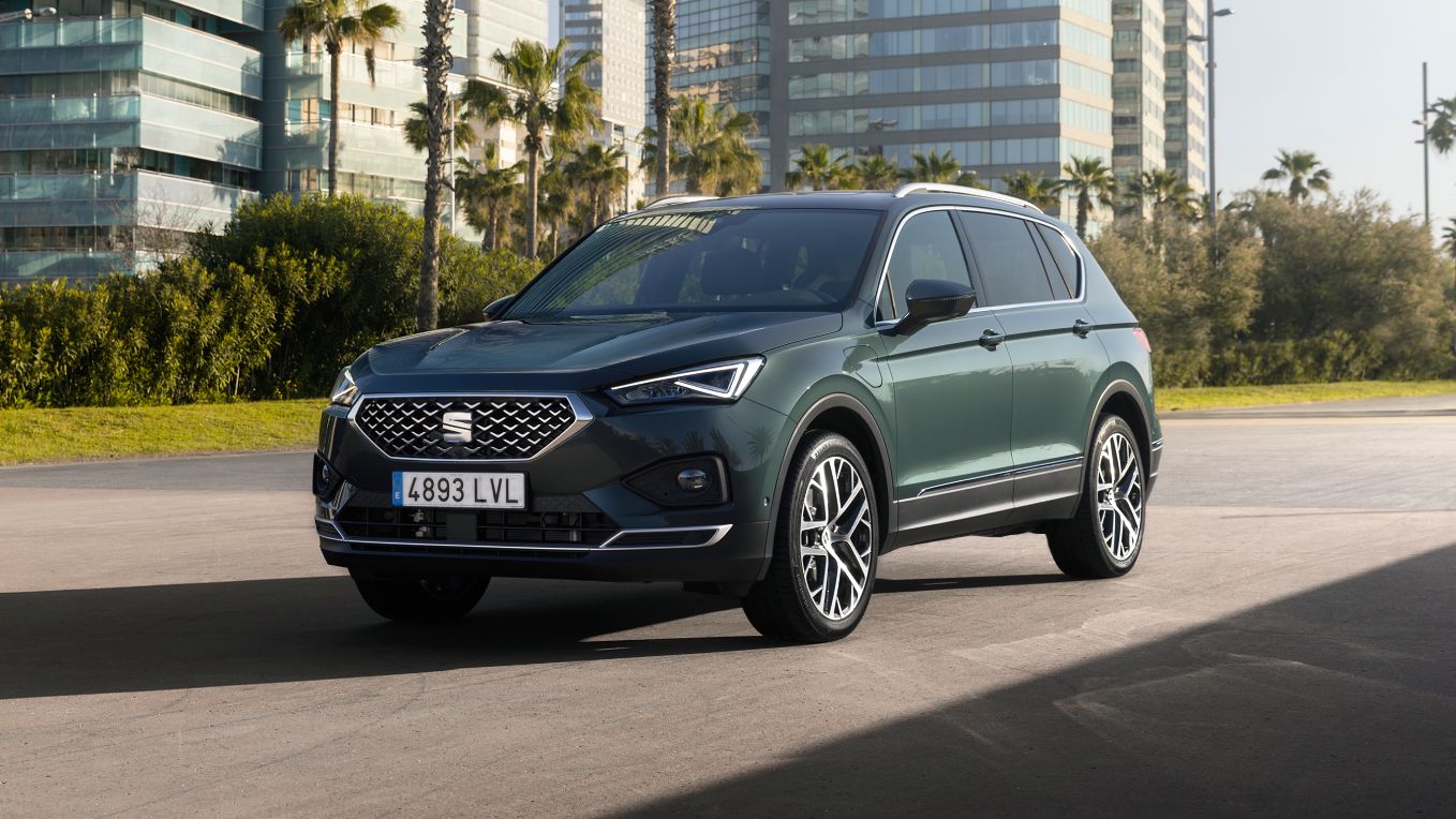 SEAT Tarraco SUV de 7 plazas híbrido enchufable en ciudad con edificios de oficinas en el fondo
