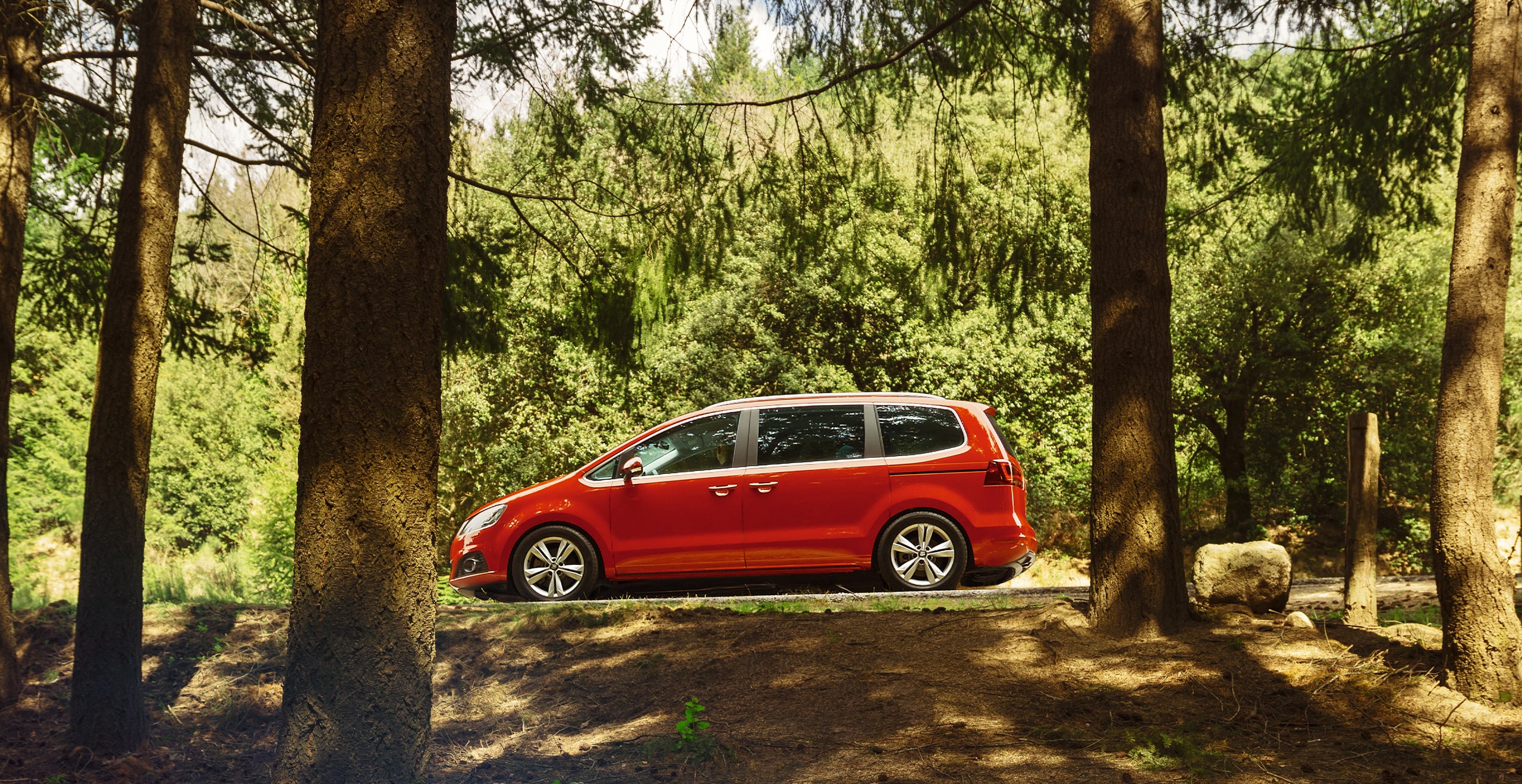 SEAT Alhambra rojo en una carretera junto al bosque