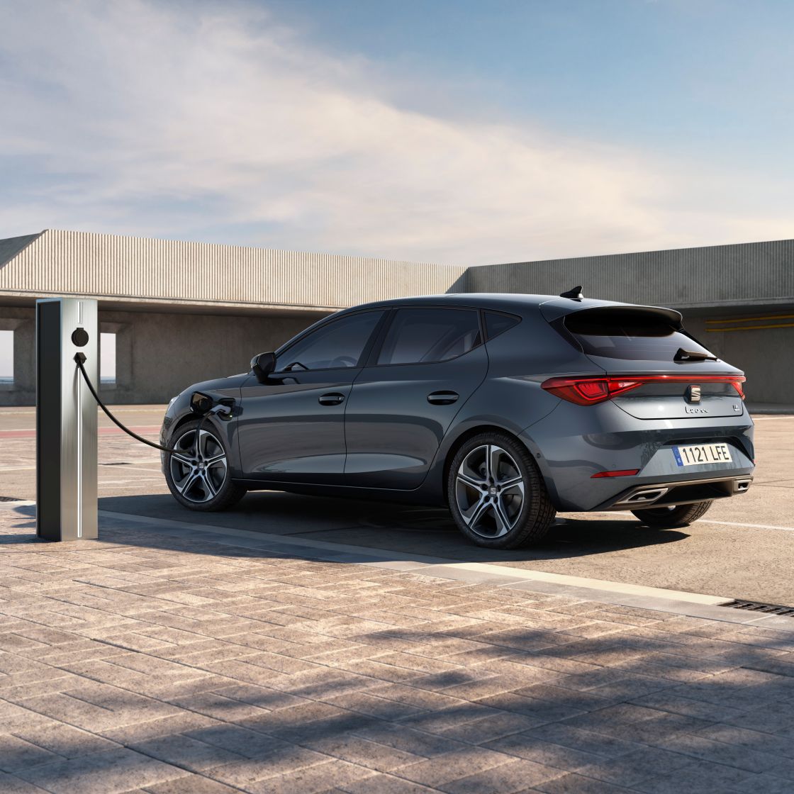 Imagen lateral trasera de un SEAT León vehículo eléctrico híbrido enchufable aparcado en una estación de carga