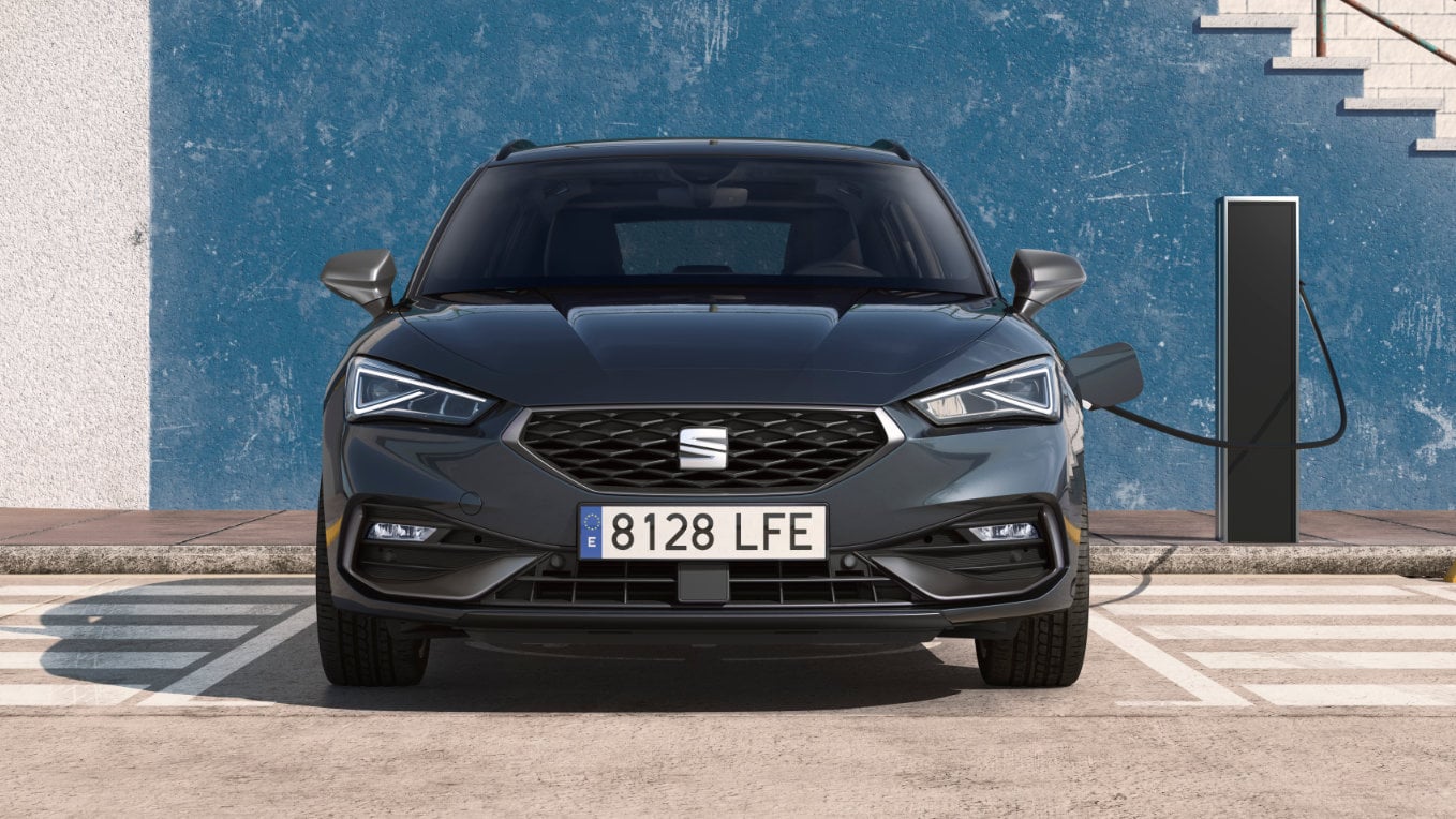 ista frontal de un SEAT León Sportstourer híbrido enchufable estacionado en un parking al aire libre cargando su batería en un punto de carga pública