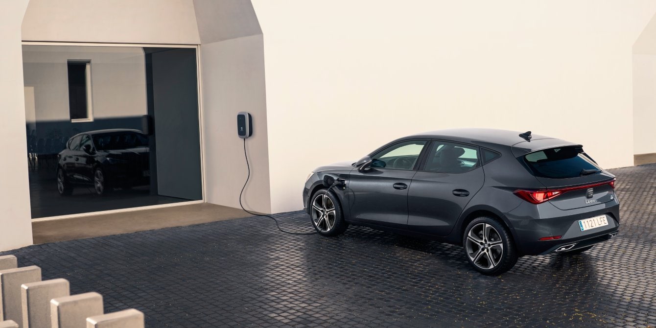 SEAT León compacto deportivo híbrido enchufable aparcado cargando su batería frente a entrada de oficinas