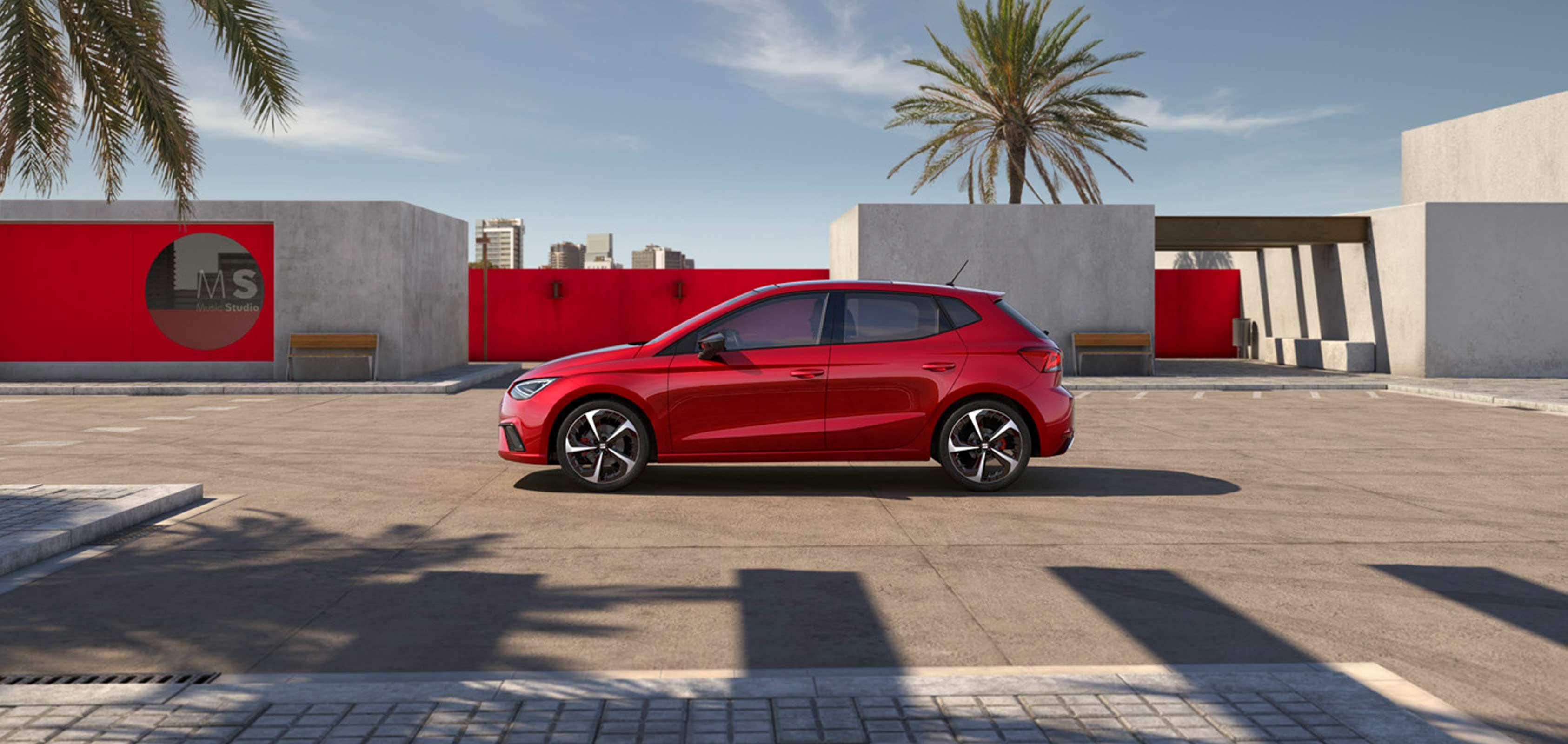 Vista lateral del SEAT Ibiza en color rojo delante de un taller