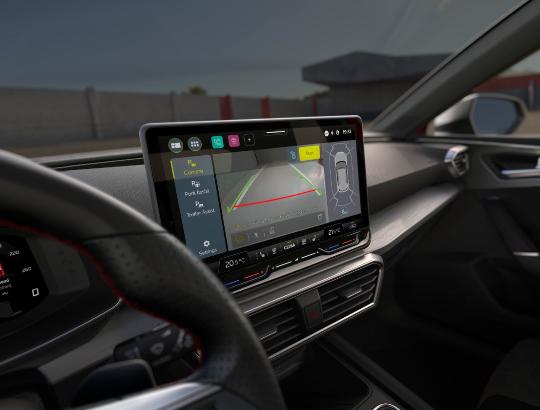 Vista interior de un SEAT León mostrando la pantalla táctil de 32,7 cm (12,9") con los asistentes Intelligent Park Assist y Trained Park Assist.