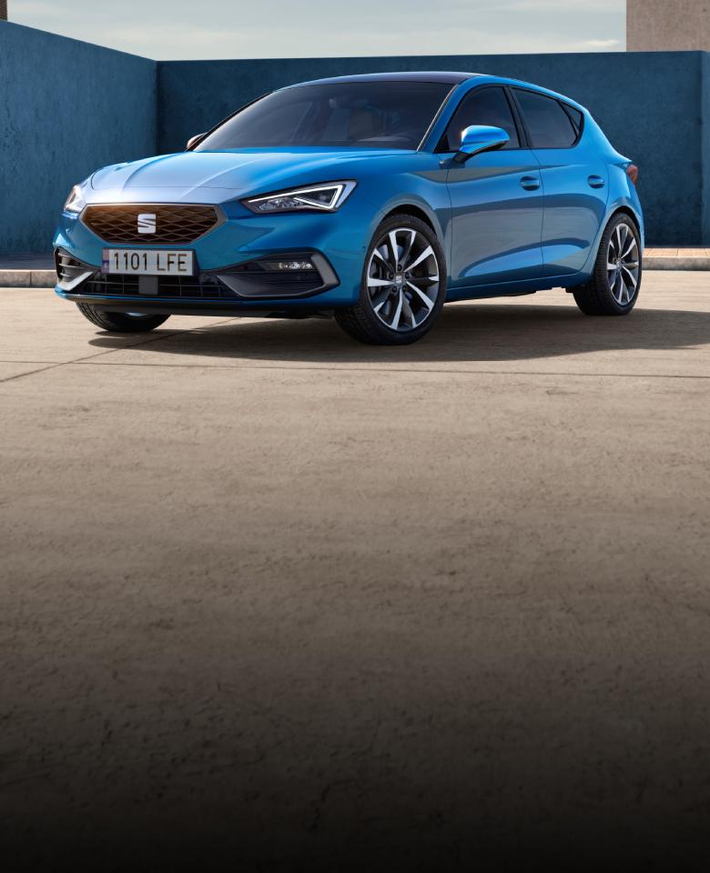 Vista en 3/4 de un SEAT León 5 puertas en color azul saphire frente a edificación modernista con muros azules