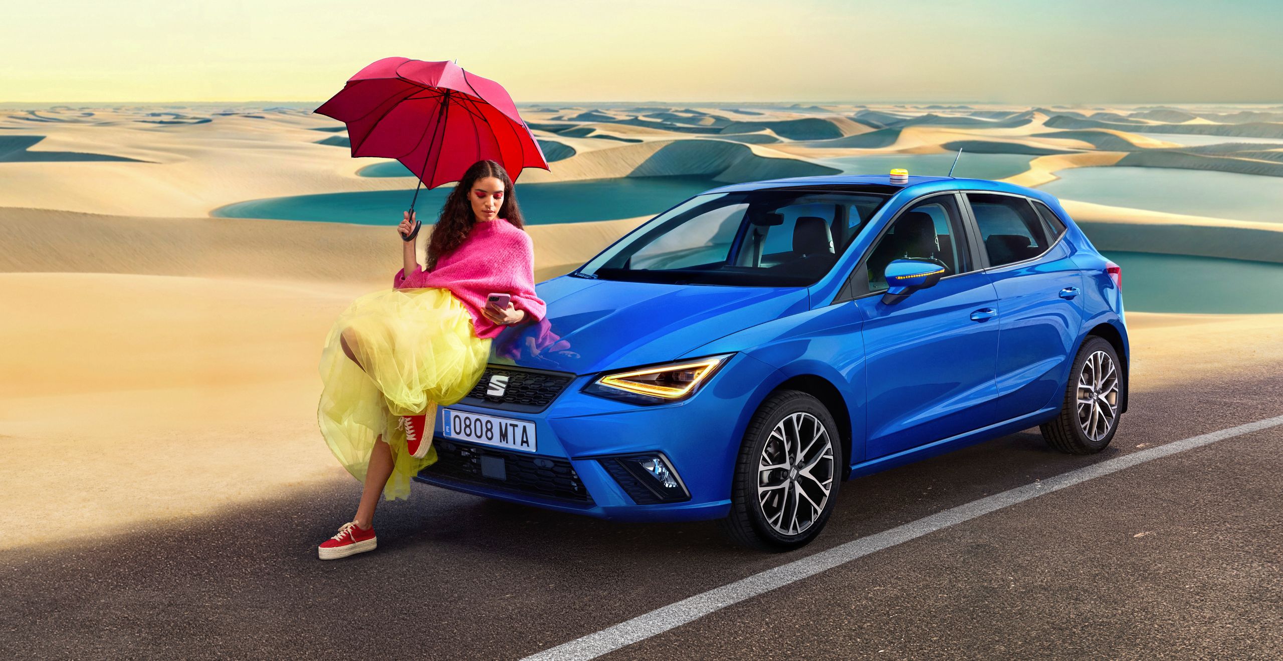 Mujer sentada sobre el capó de SEAT Ibiza azul