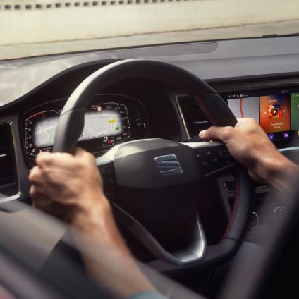 Hombre y mujer recargando SEAT Leó híbrido eléctrico enchufable en escenario con dunas