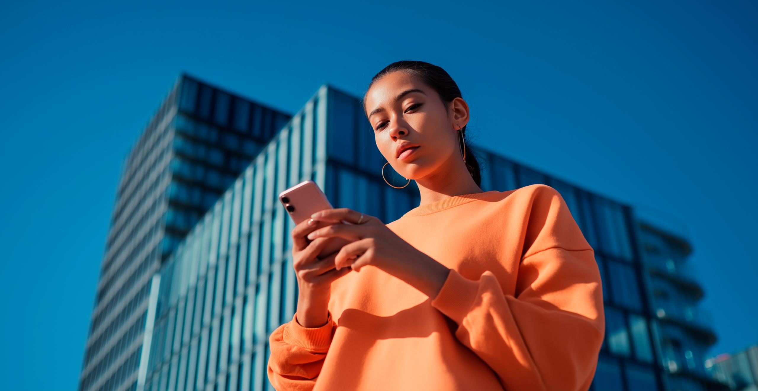 Mujer consulta la calculadora de mantenimiento de su SEAT en smartphone; fondo con edificio acristalado