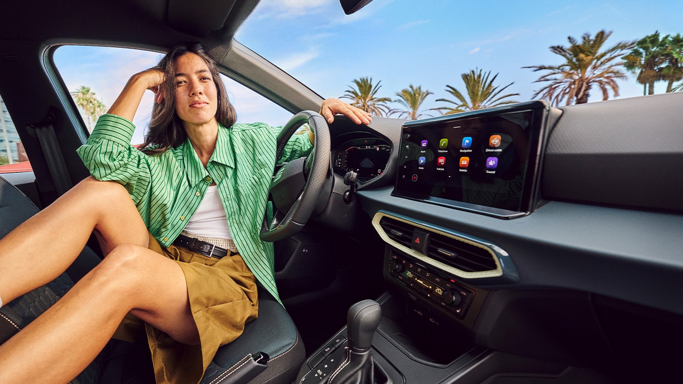 Vista interior del SEAT Arona, en la que se aprecia el avanzado sistema de navegación, con una pantalla de 9,2 pulgadas y un elegante entorno urbano en el exterior.