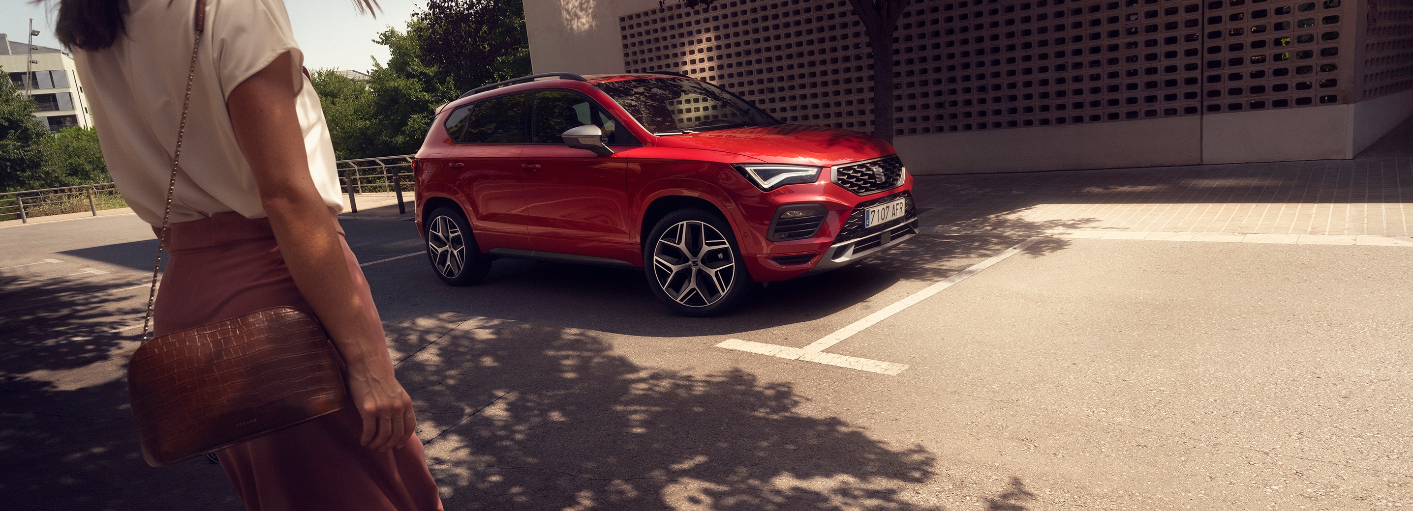 una persona se acerca a un SEAT Ateca rojo aparcado en la calle
