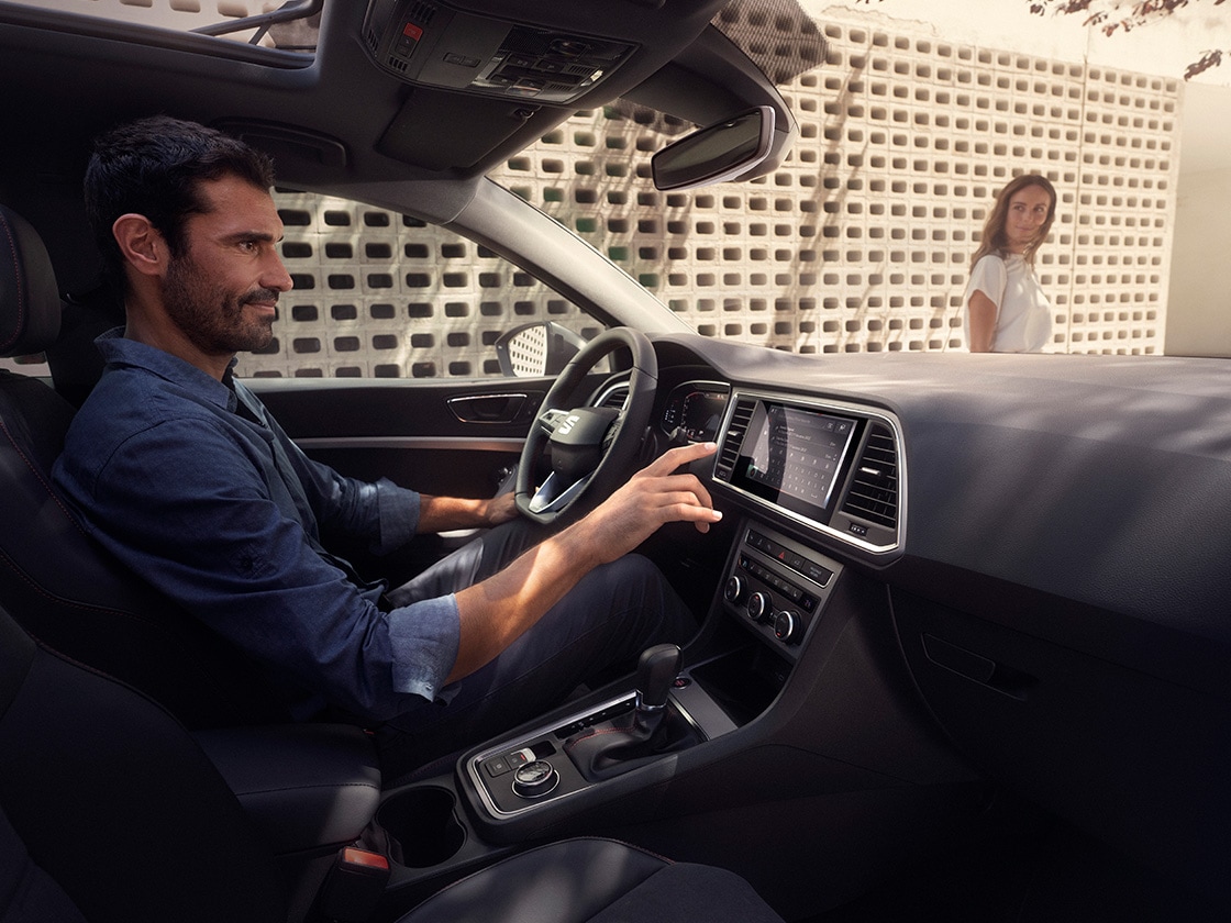 Un hombre disfruta conduciendo el SEAT Ateca mientras una mujer mira desde fuera.