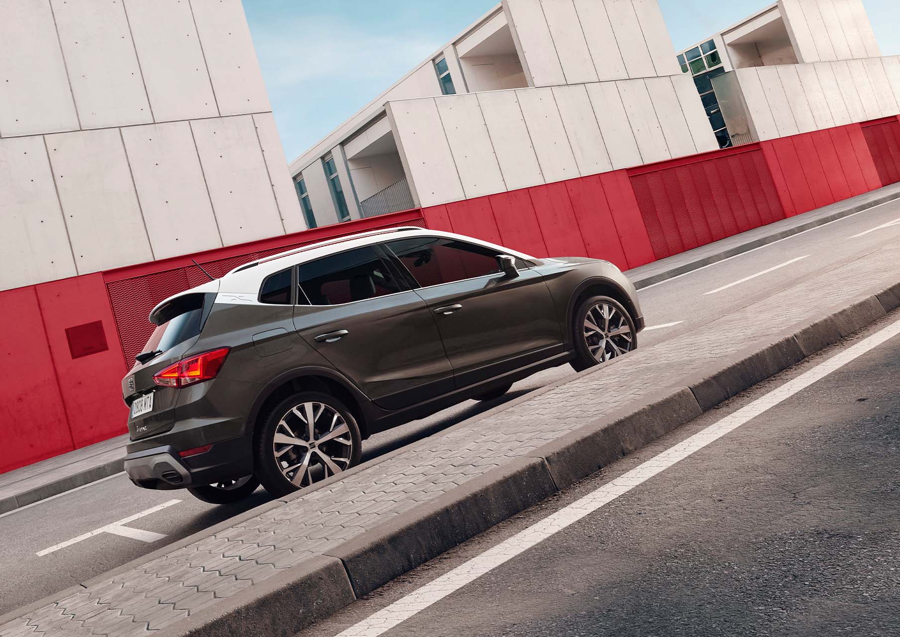 SEAT Arona de color gris Cliff aparcado en acera junto a edificios de hormigón 