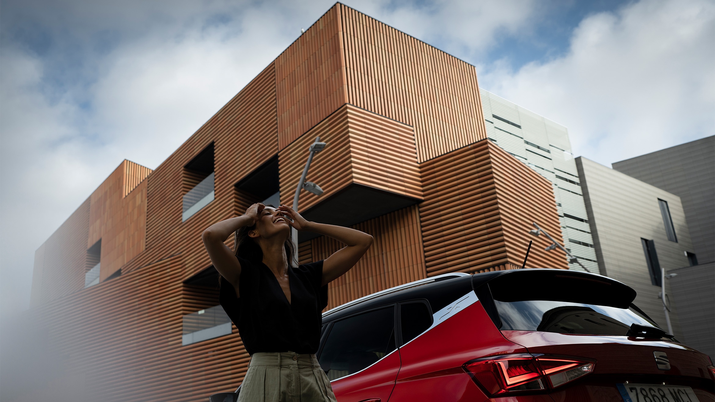 SEAT Arona SUV urbano color rojo Desire con techo bicolor junto a mujer alegre