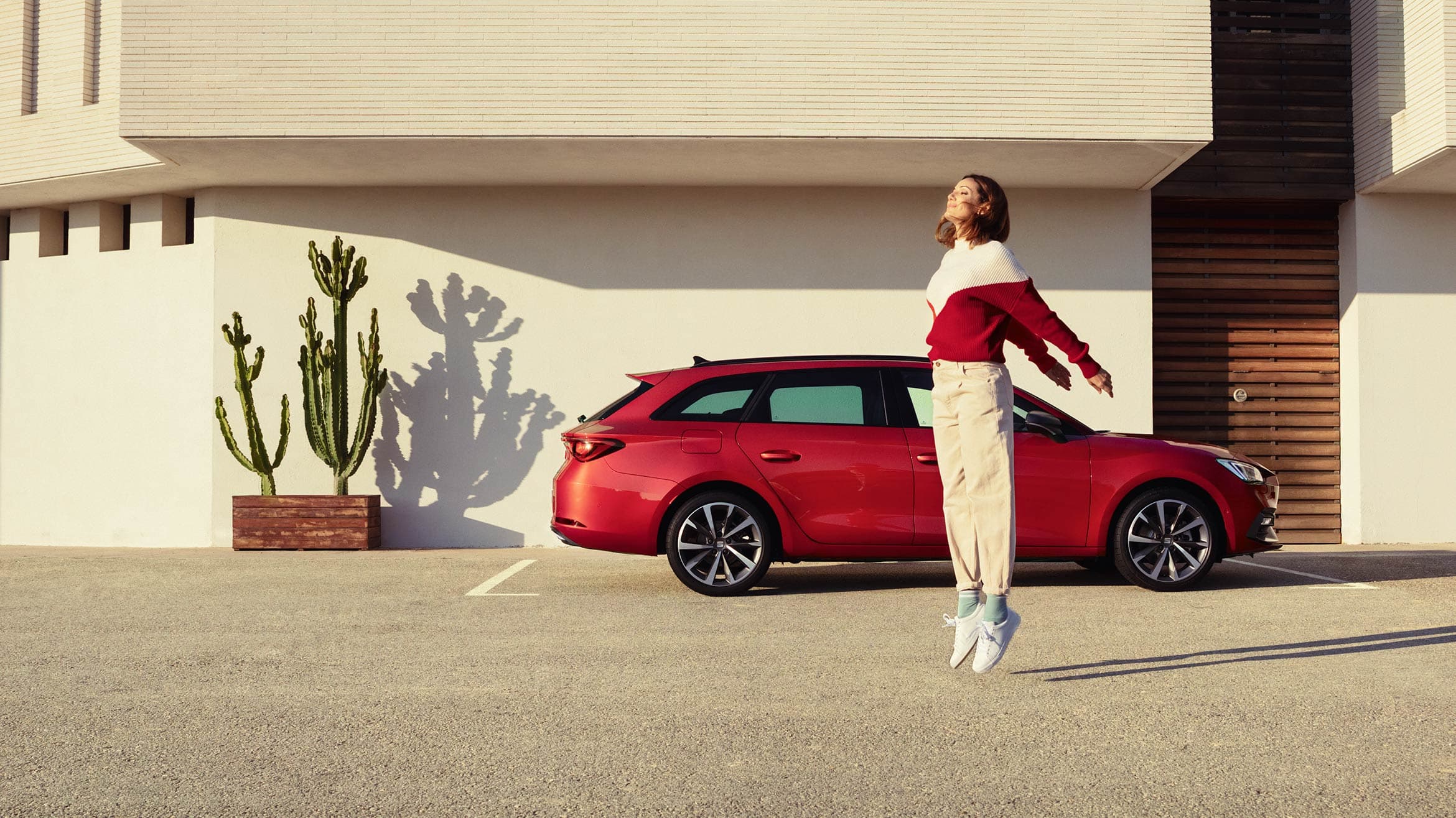 mujer de pie junto al SEAT León Sportstourer color rojo Desire