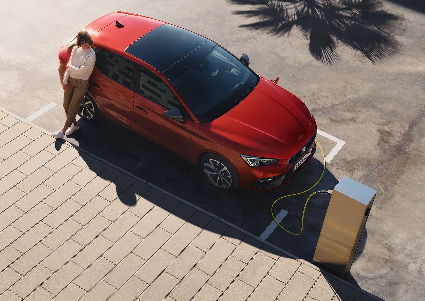 mujer cargando el SEAT León 5 puertas e-hybrid color rojo Desire