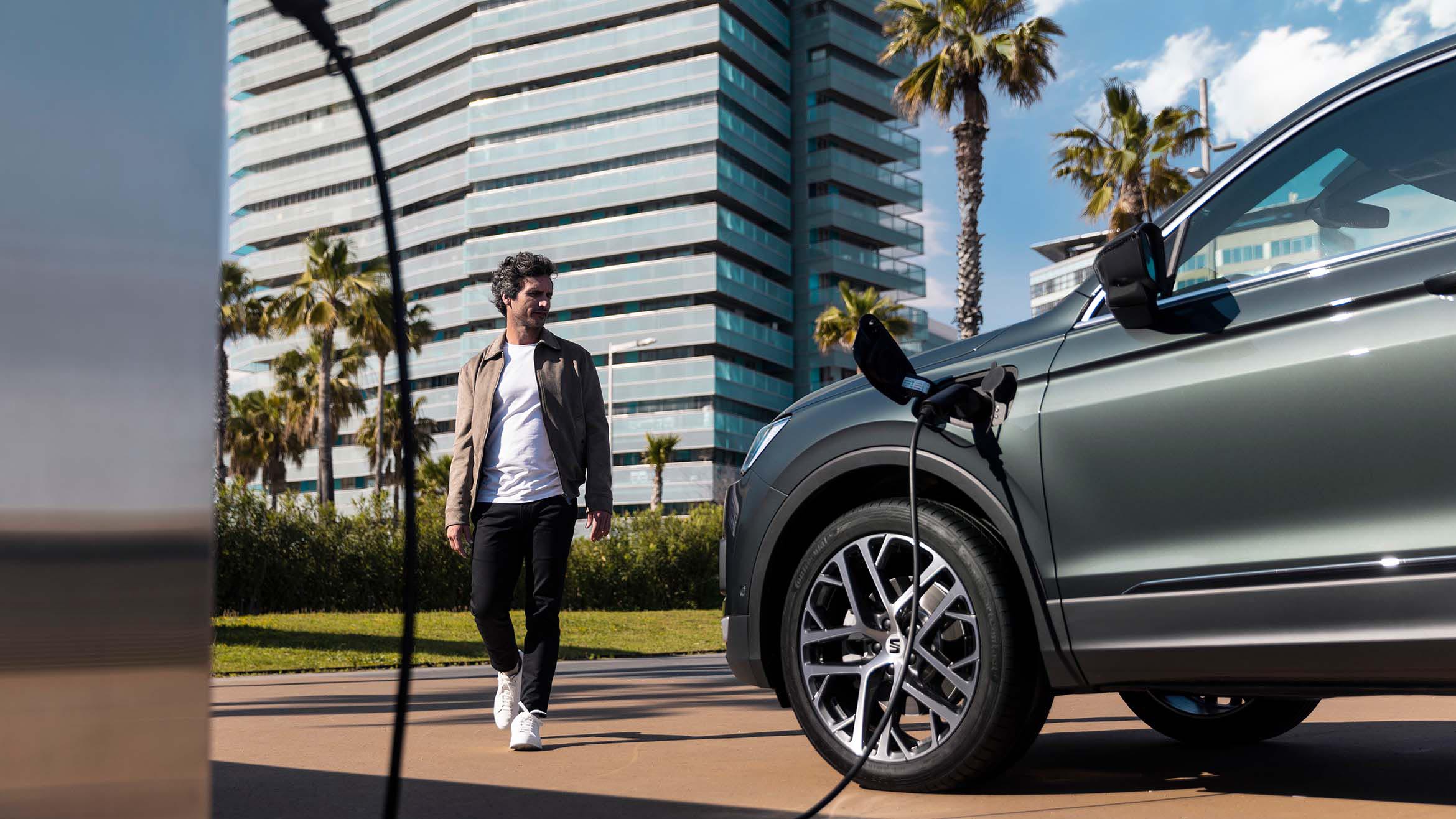 Hombre delante del nuevo SEAT Tarraco XPERIENCE color Dark Camouflage cargándose con llantas de aleación-
