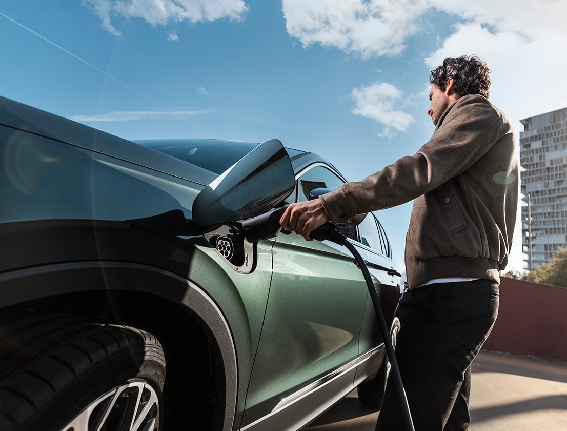 Hombre cargando el SEAT Tarraco XPERIENCE e-HYBRID en color Dark Camouflage   