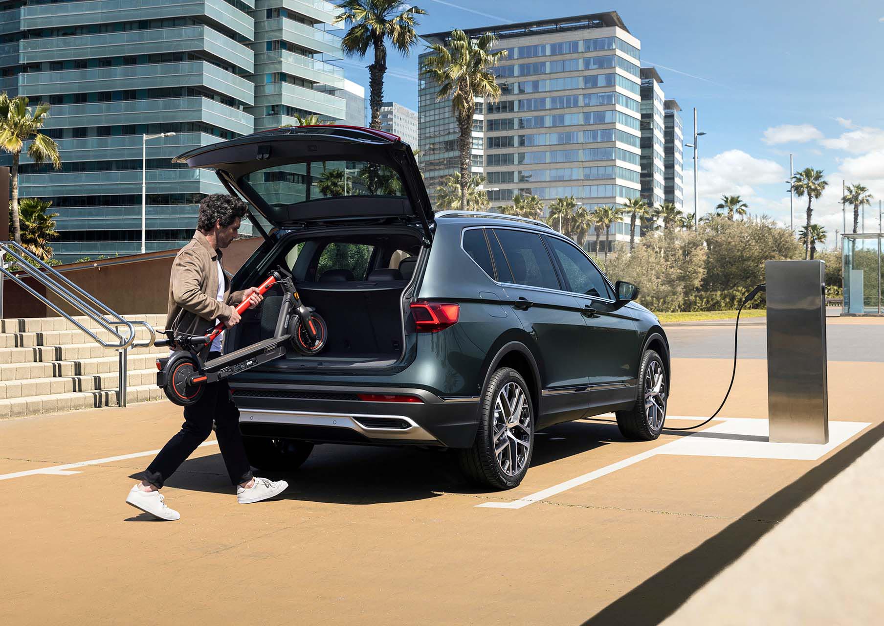 Hombre guardando un SEAT MÓ 65 en el interior del maletero del nuevo SEAT Tarraco XPERIENCE