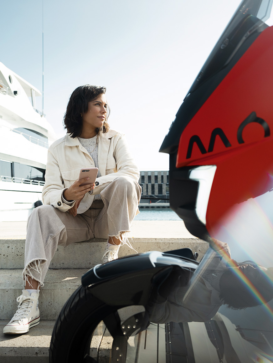 mujer sentada en su SEAT MÓ eléctrico aparcada en el puerto