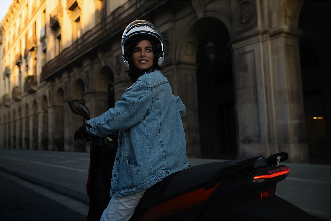 mujer conduciendo su scooter SEAT MÓ 125 eléctrico con una velocidad máxima de 95 km/h