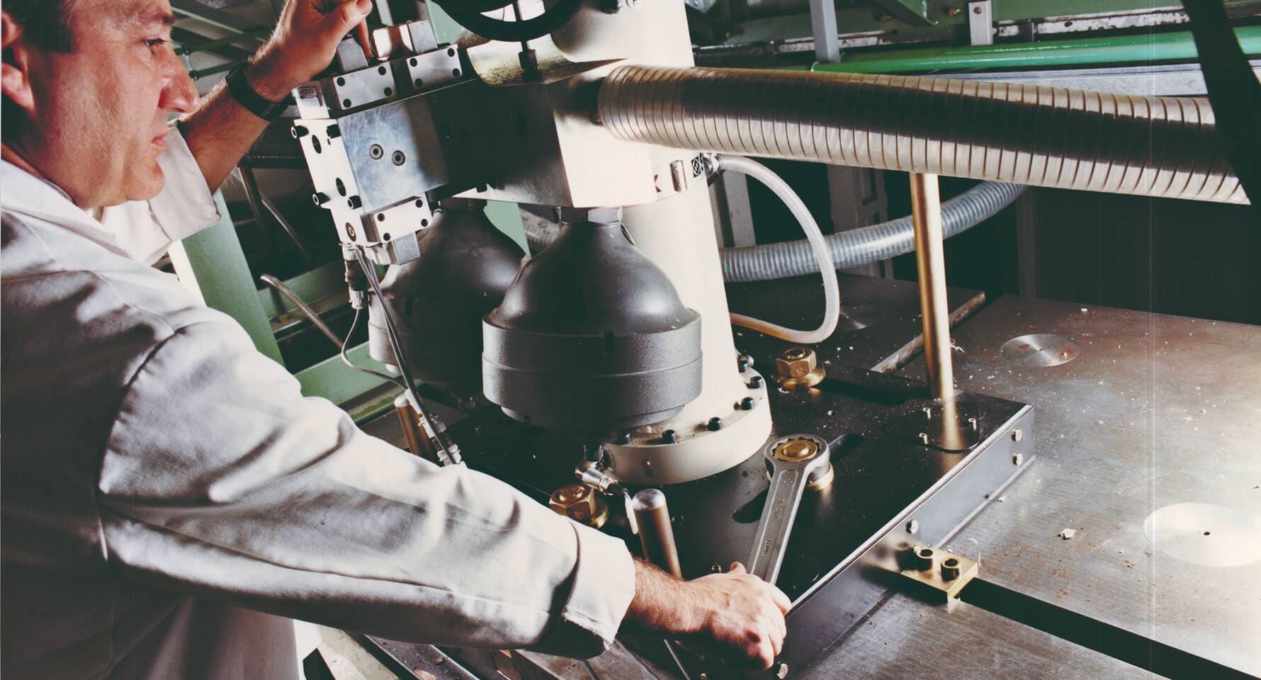 Un hombre con bata blanca operando cuidadosamente una máquina industrial